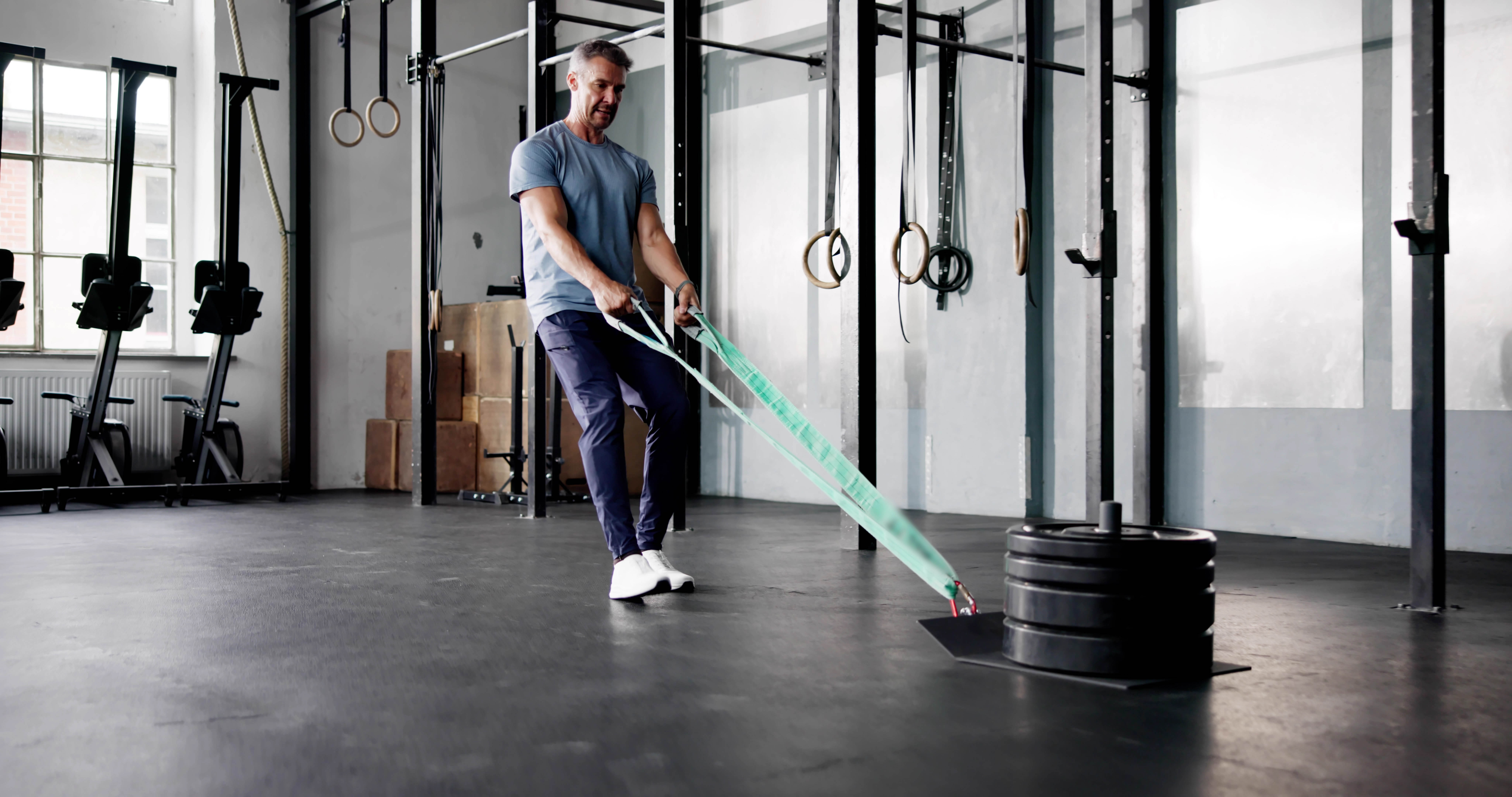 Man doing a backwards sled pull in a gym Man doing a backwards sled pull in a gym